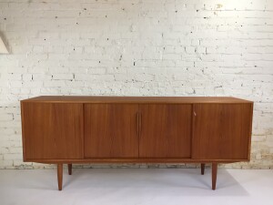 Outstanding Mid-century Modern teak credenza by Axel Christensen Odder. Made in Denmark - this fabulous example has sculptural solid teak handles with subtly tapered solid teak legs. The middle of the chest has three dovetailed pull-out drawers while the left and right sides have adjustable shelves. This is an ideal piece that can be used as a living room media cabinet, dining room sideboard, or office credenza - newly refinished - (SOLD)